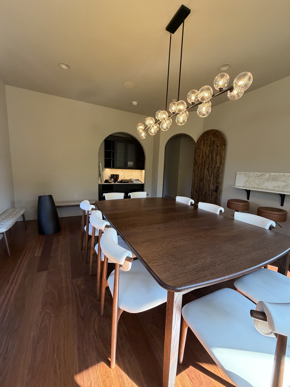 Linear glass globe chandelier over a long wooden dining table